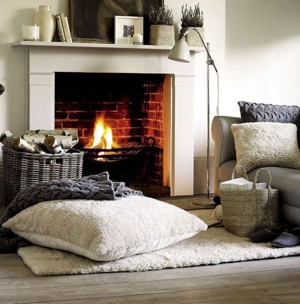 A modern living room with plenty of cozy blankets, pillows, and a roaring fire A modern living room with plenty of cozy blankets, pillows, and a roaring fire