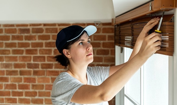Woman removing her mini blinds with a screwdriver