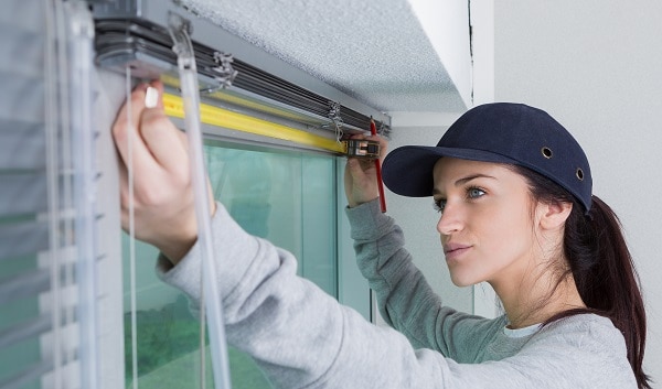 a young woman about to embark on her home DIY journey by repairing her horizonal window blinds