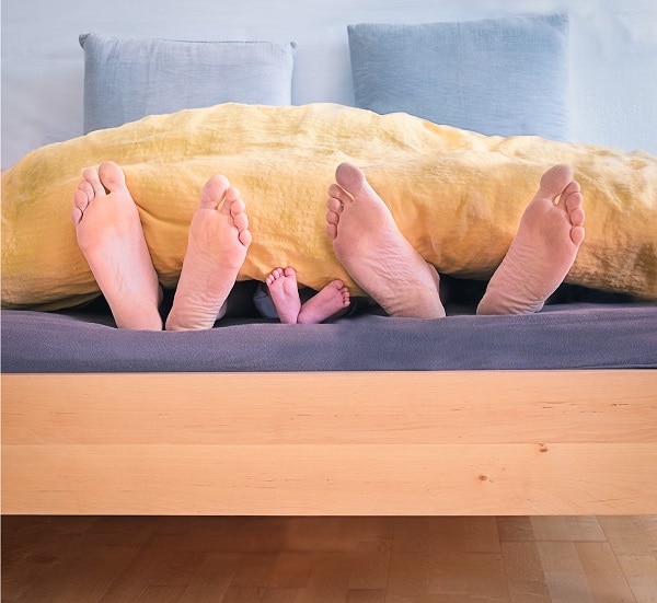A few pairs of bare feet sticking out of the bedsheets at night. Source: Unsplash