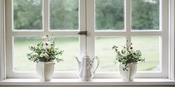 Minimalist decor on a window sill looking into a green outdoor patio space.