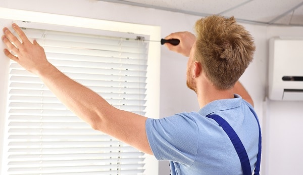 Male professional installing window blinds