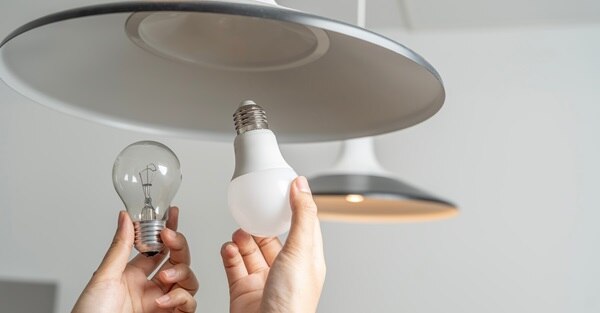 a pair of hands replacing fluorescent light bulbs (CFL) with new LED bulbs to save energy on your monthly bill